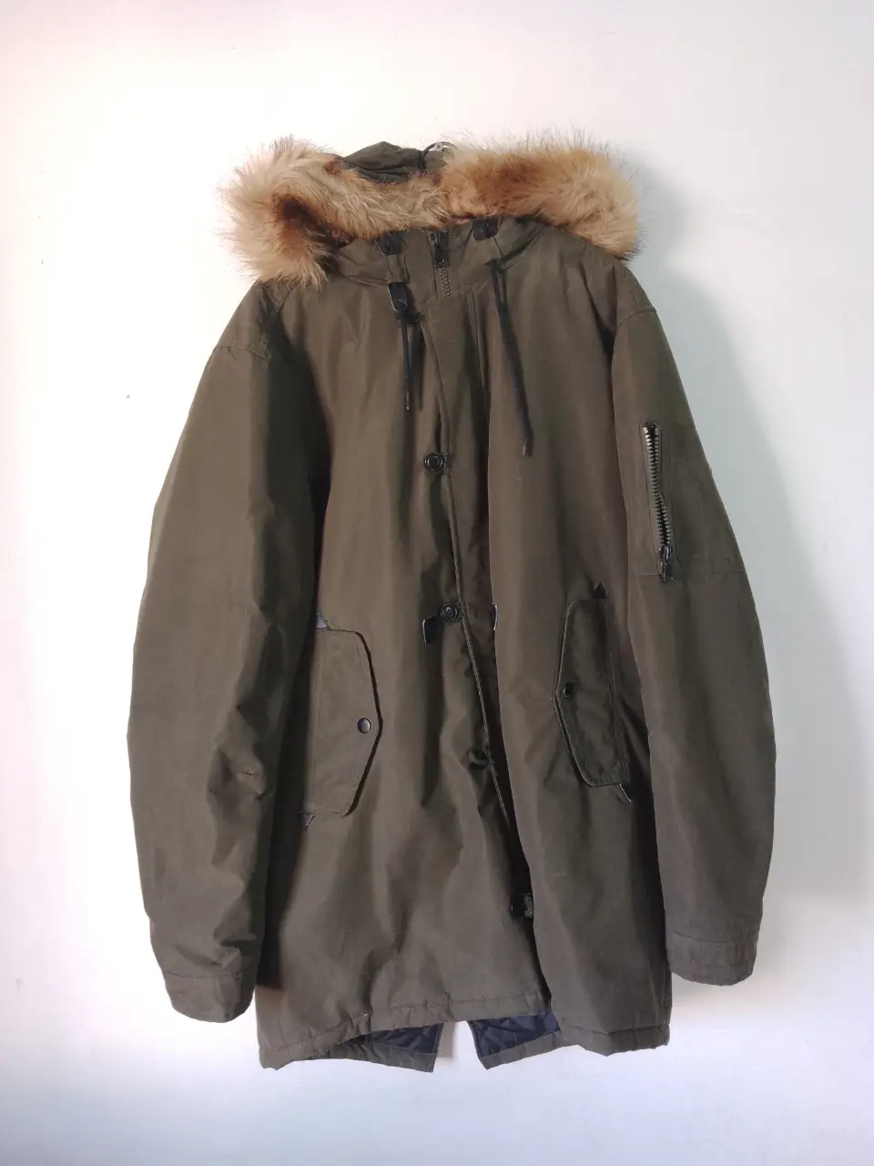 Campera parka verde oscuro con capucha de piel sintética. Ideal para el invierno, con bolsillos y cierre.