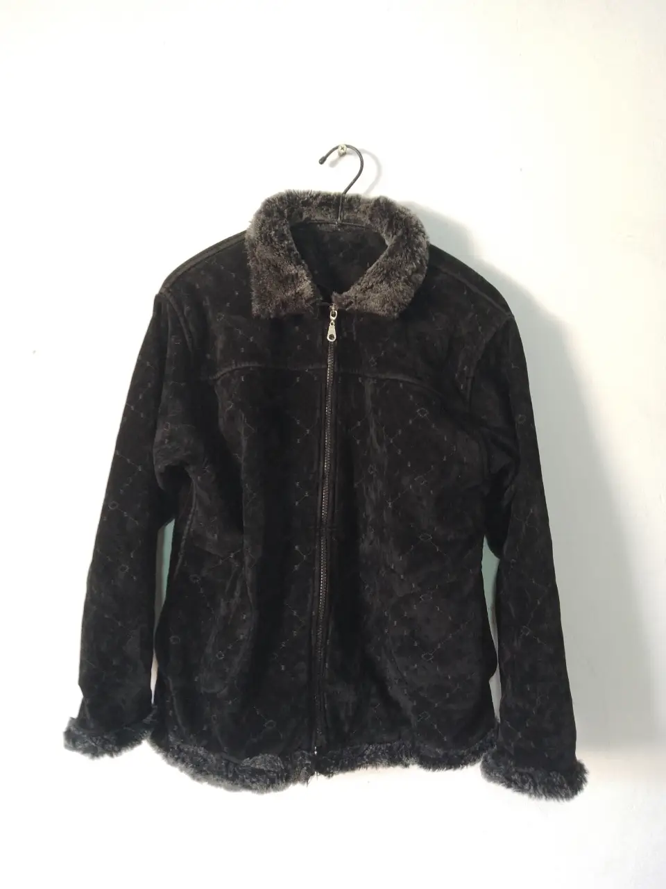Campera bomber de terciopelo negro con cuello y puños de piel sintética. Cierre con cremallera y detalles de diseño en la tela.