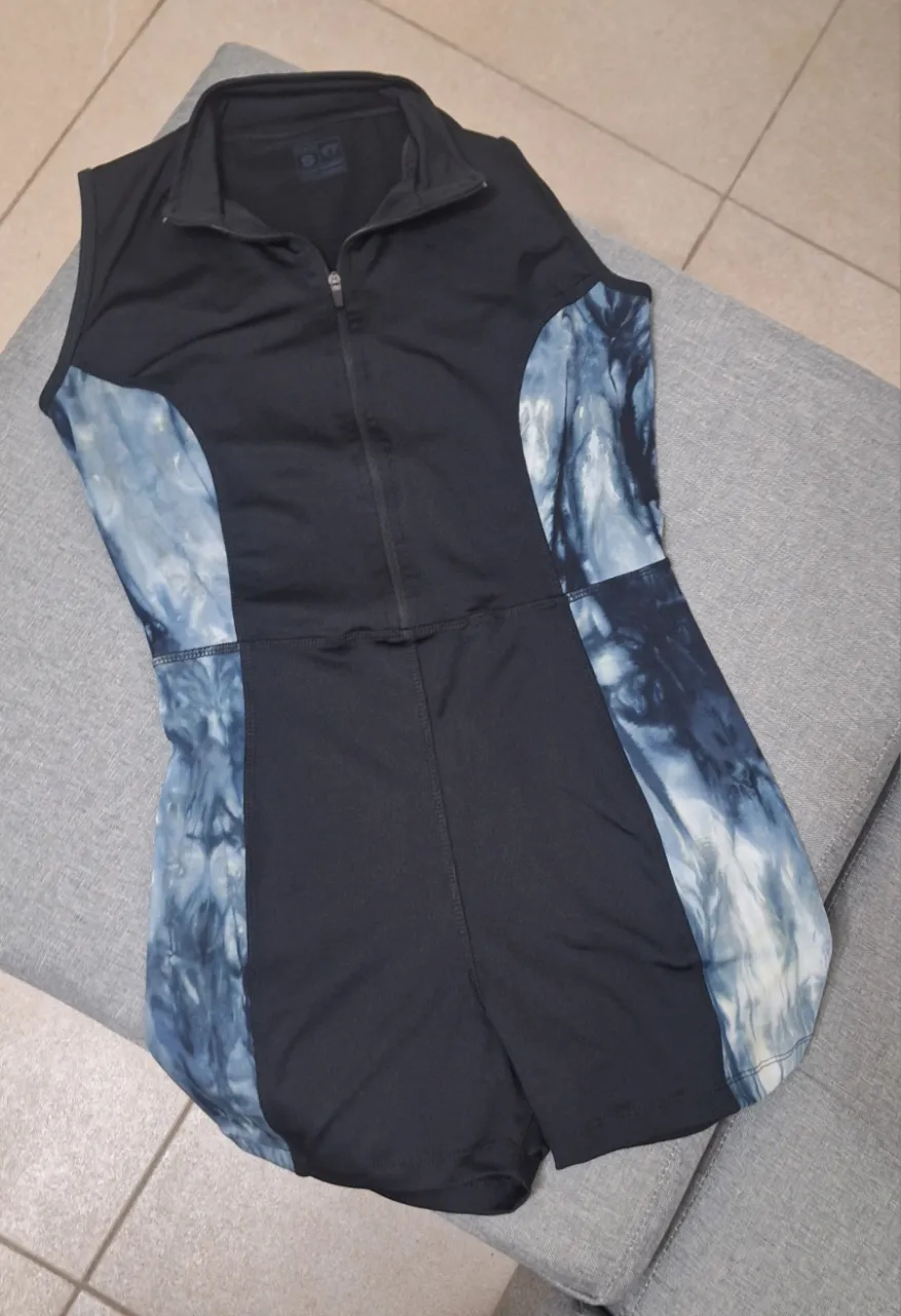 Mono corto deportivo para mujer, con cierre frontal y detalles en azul con estampado. Ideal para actividades físicas.