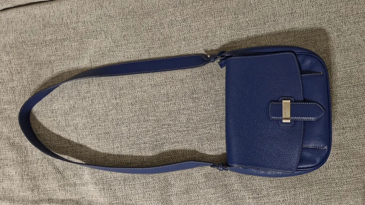 Cartera de hombro azul de cuero con cierre y detalles en plateado. Ideal para un look elegante y sofisticado.