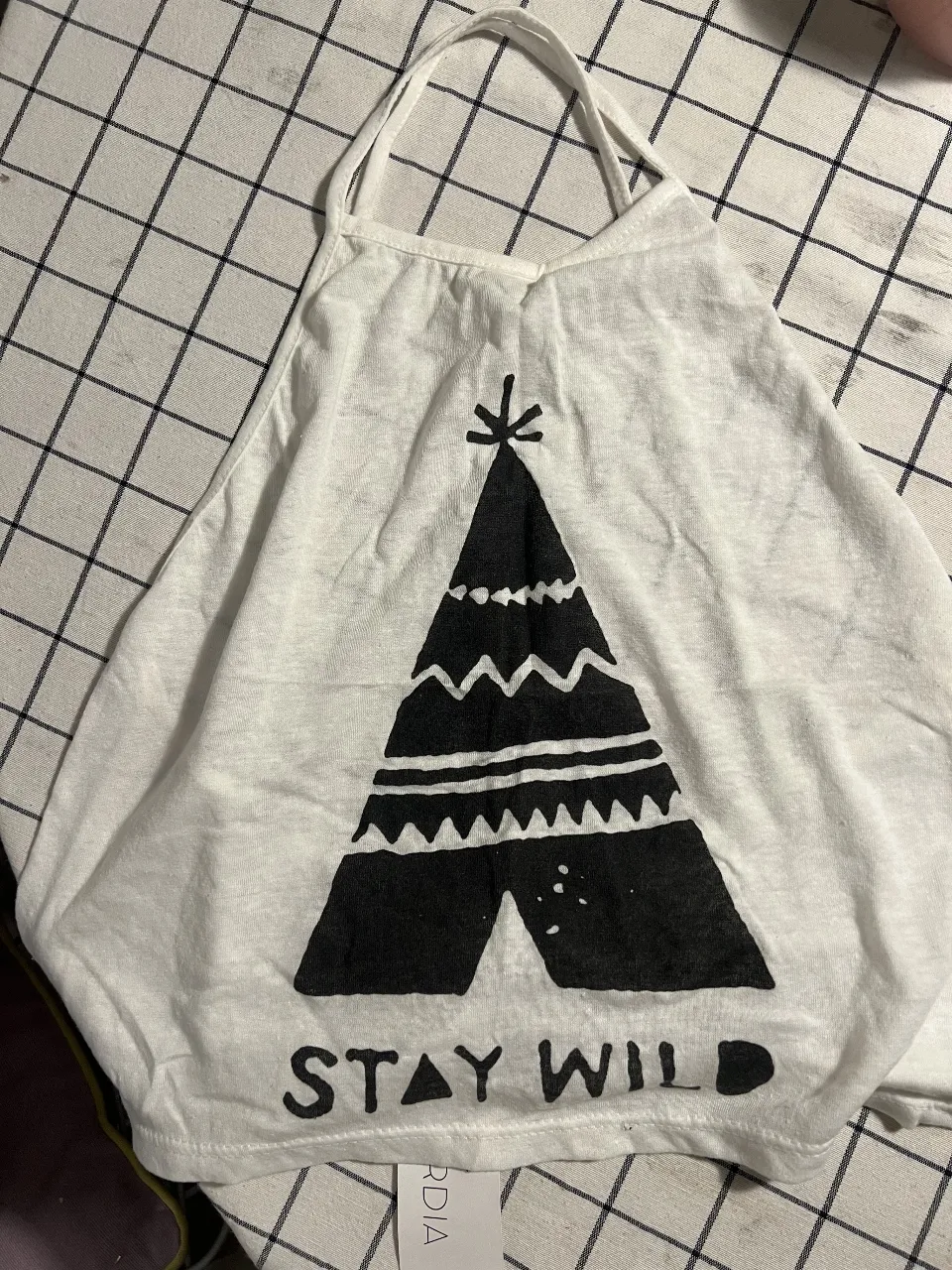 Musculosa blanca con estampa de tipi y la frase "STAY WILD". Ideal para un look relajado y con onda.