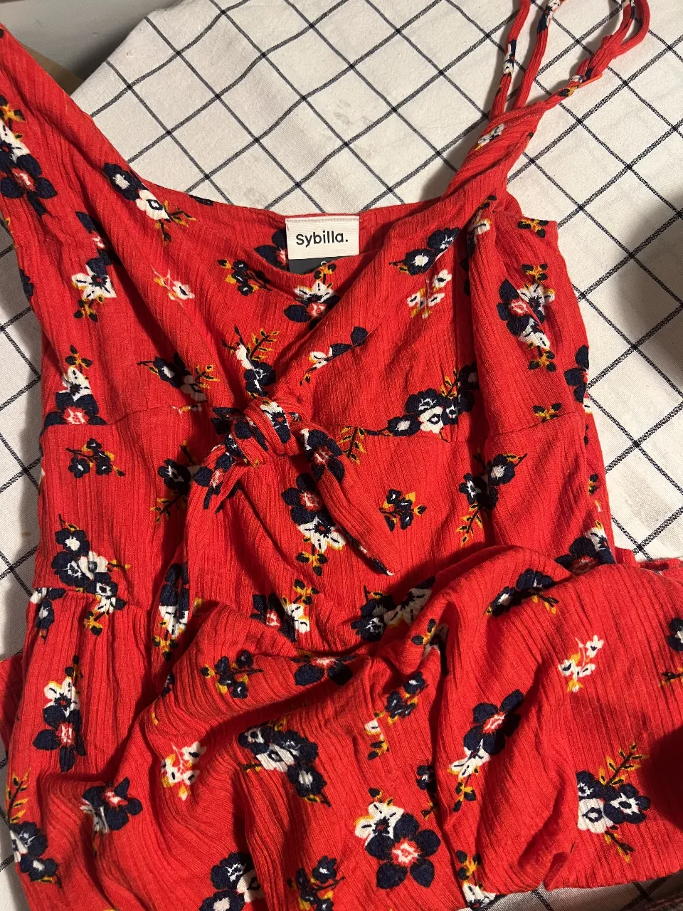 Vestido short  rojo vibrante con estampa floral de flores azules y blancas. Diseño con breteles finos y detalle de lazo en el busto. Ideal para un look fresco y femenino.