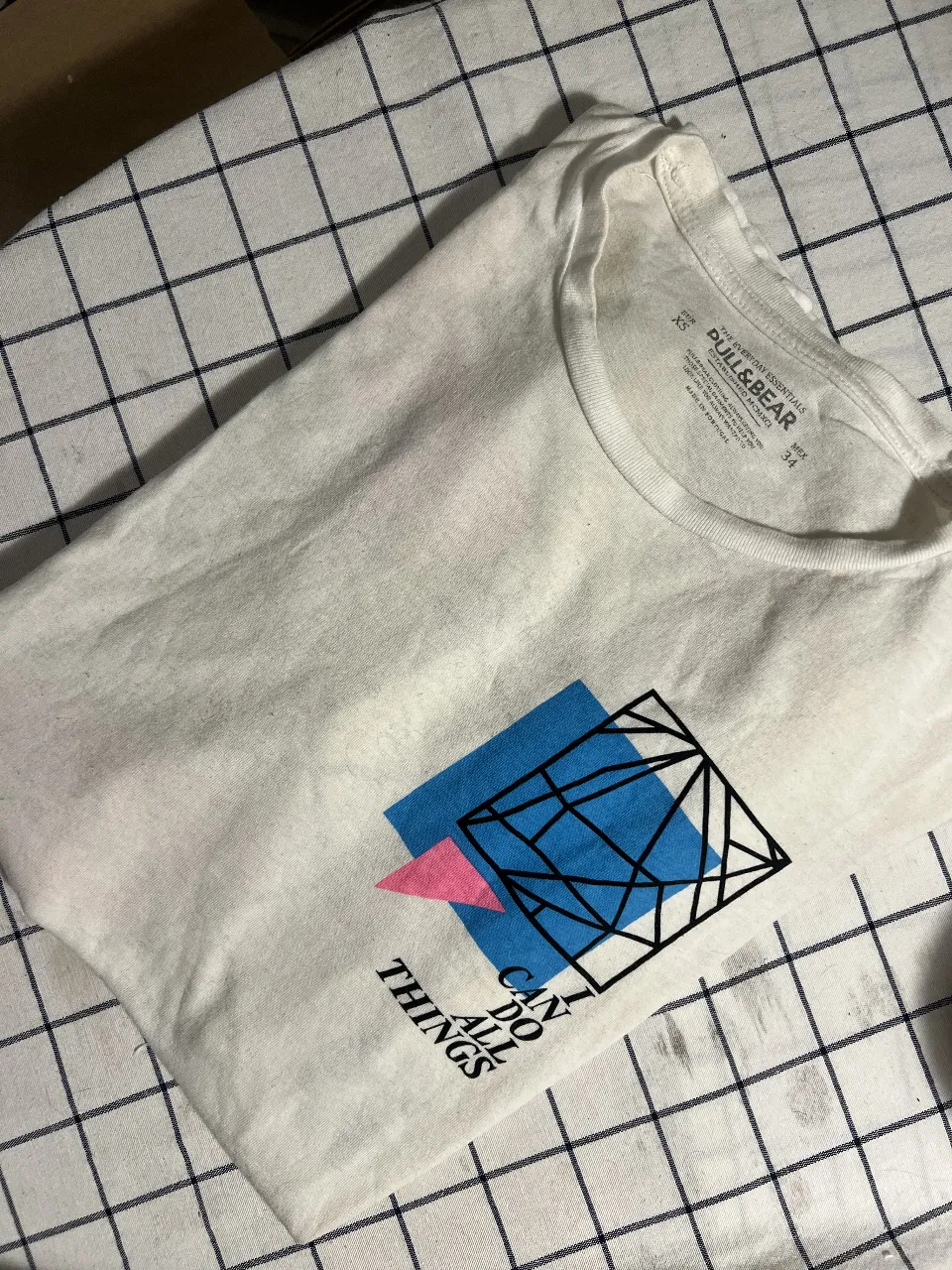 Remera blanca de manga corta con estampa gráfica abstracta en la espalda y adelante. "I CAN DO ALL THINGS" y "#1991" son parte del diseño. Ideal para un look casual y moderno.