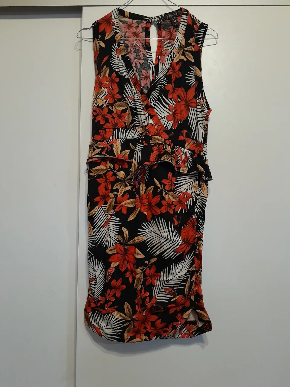 Vestido midi con estampado floral en tonos rojos y blancos sobre fondo negro. Diseño con escote en V, detalle de fruncido en la cintura y falda con abertura lateral. Ideal para un look fresco y femenino.