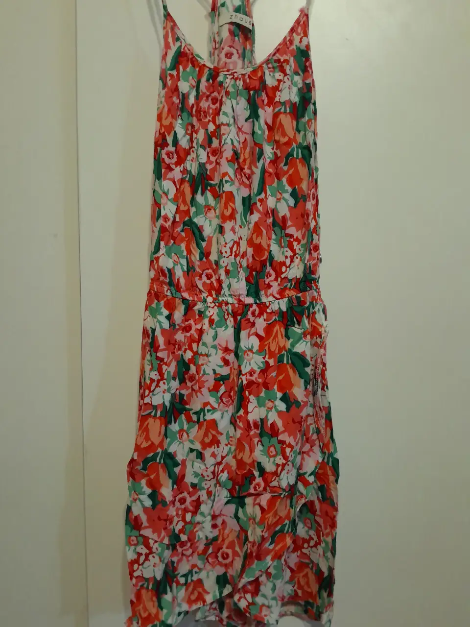Vestido midi de mujer con estampado floral en tonos rojos, blancos y verdes. Diseño con tirantes finos y detalle fruncido en la cintura. Ideal para un look fresco y femenino.