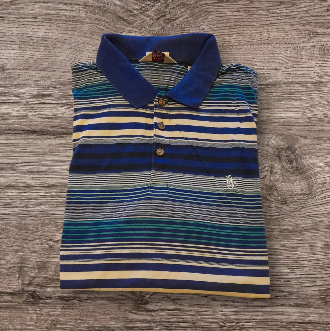 Remera polo de hombre con diseño a rayas en tonos azul, amarillo y blanco. Cuello y mangas en azul marino. Ideal para un look casual y fresco.