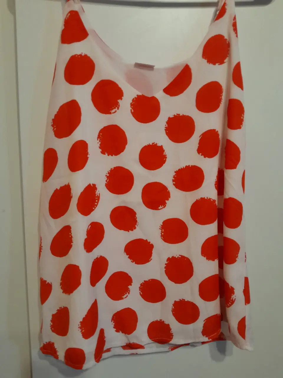 Top de mujer con estampado de lunares rojos sobre fondo blanco. Ideal para un look fresco y veraniego.