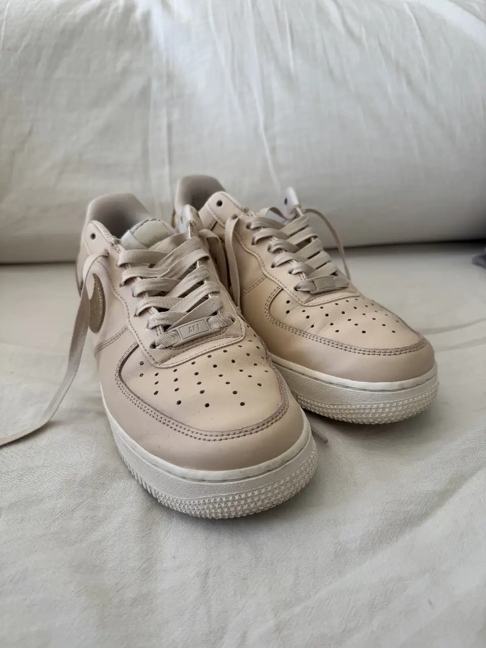 Zapatillas Nike Air Force 1, color crema con detalles dorados en el logo y talón. Un clásico atemporal para un look casual y cómodo.