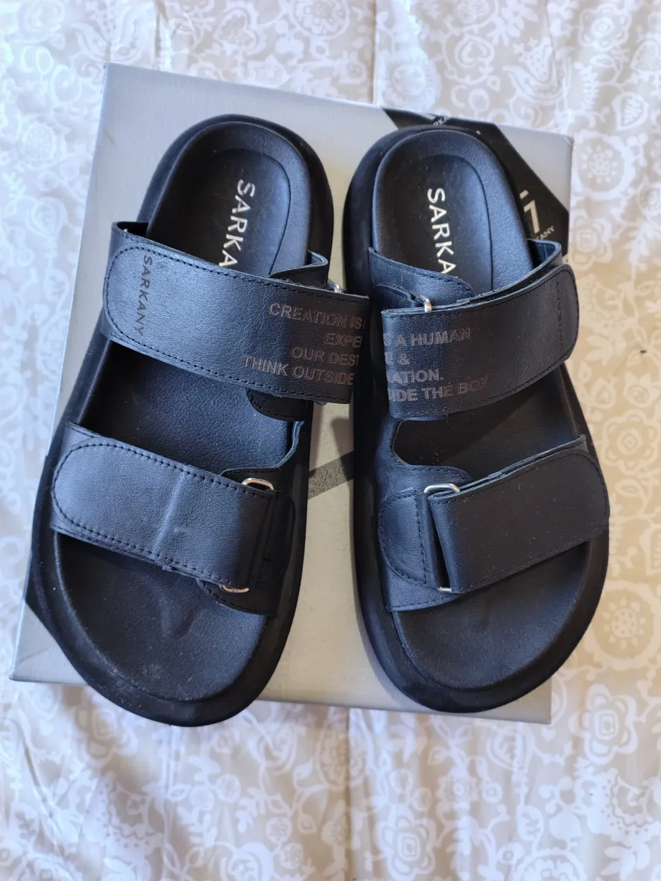 Sandalias Sarkany negras con dos tiras ajustables y suela gruesa. Ideales para un look casual y cómodo.