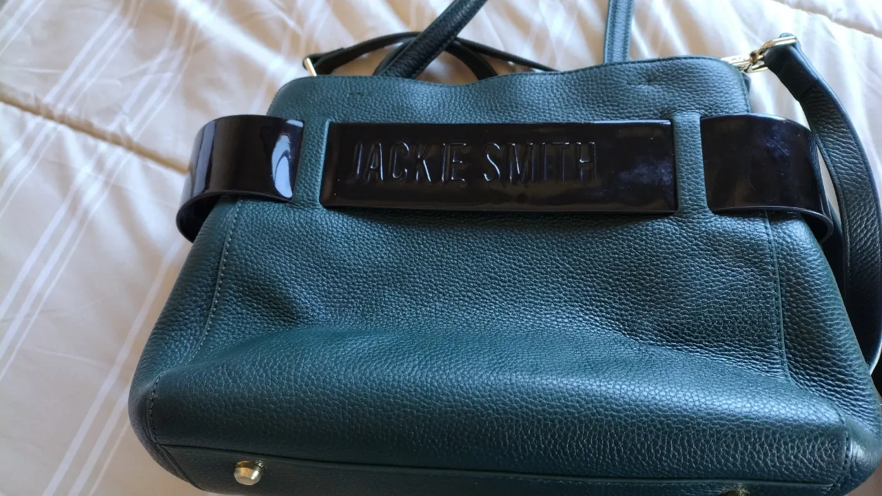 Cartera Jackie Smith de cuero, color verde oscuro, con detalles en negro y cierre dorado. Ideal para llevar tus esenciales con estilo y elegancia.