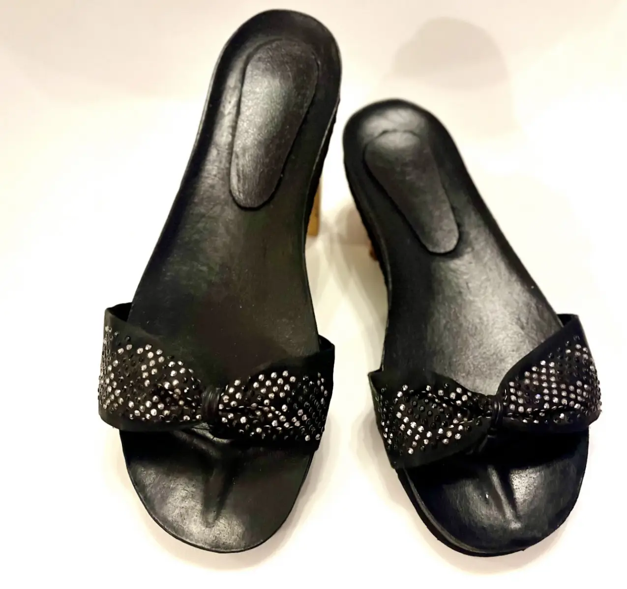 Sandalias negras con moño adornado con brillos. Ideales para un look elegante y cómodo.