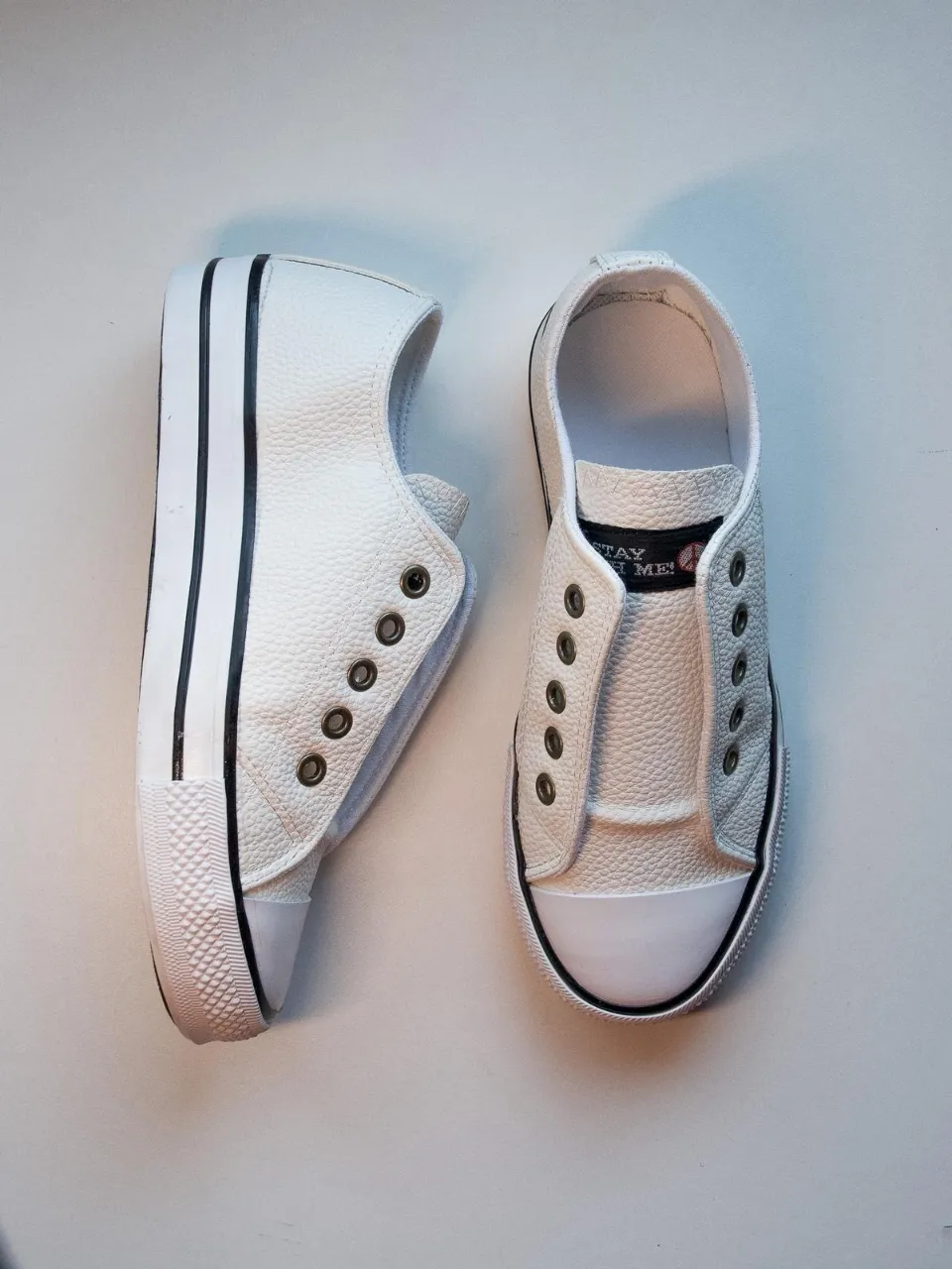 Zapatillas cuero sintético blancas con detalle en negro. Diseño clásico y versátil, ideales para un look casual y cómodo. Perfectas para combinar con cualquier outfit.