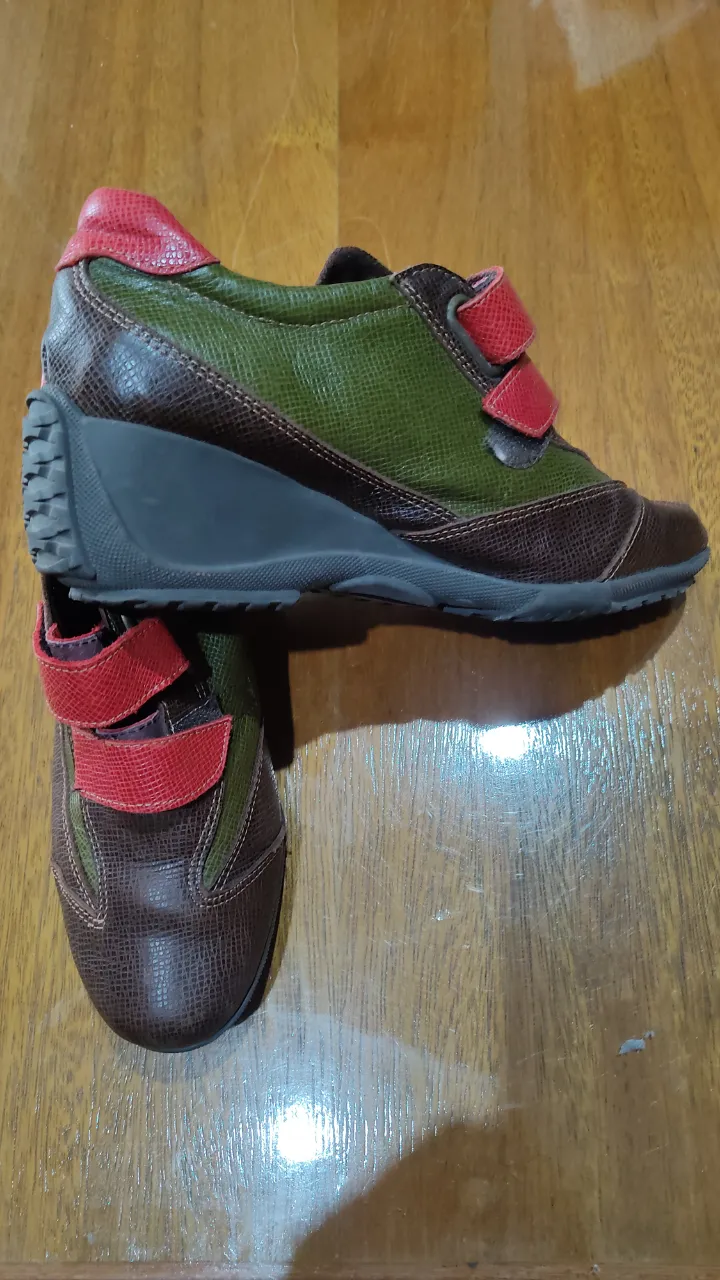 Zapatillas de cuero con velcro. Horma para pie delgado. Combinan cuero marrón texturizado con paneles de cuero verde. Tienen detalles en cuero rojo en el talón y en las tiras de velcro. Suela de goma con buen agarre. Altura en el taco 4,5 cm. en la parte mas alta.
 Impecables. 