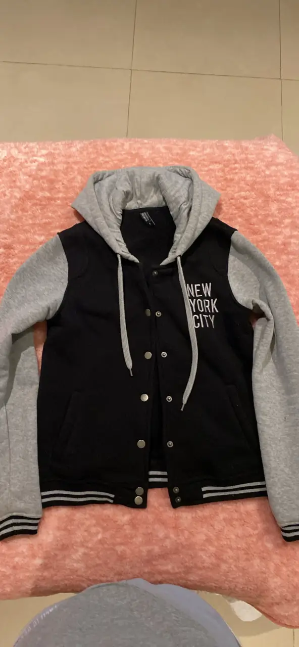 Campera NYC  con capucha y cierre, de color negro con mangas grises. 