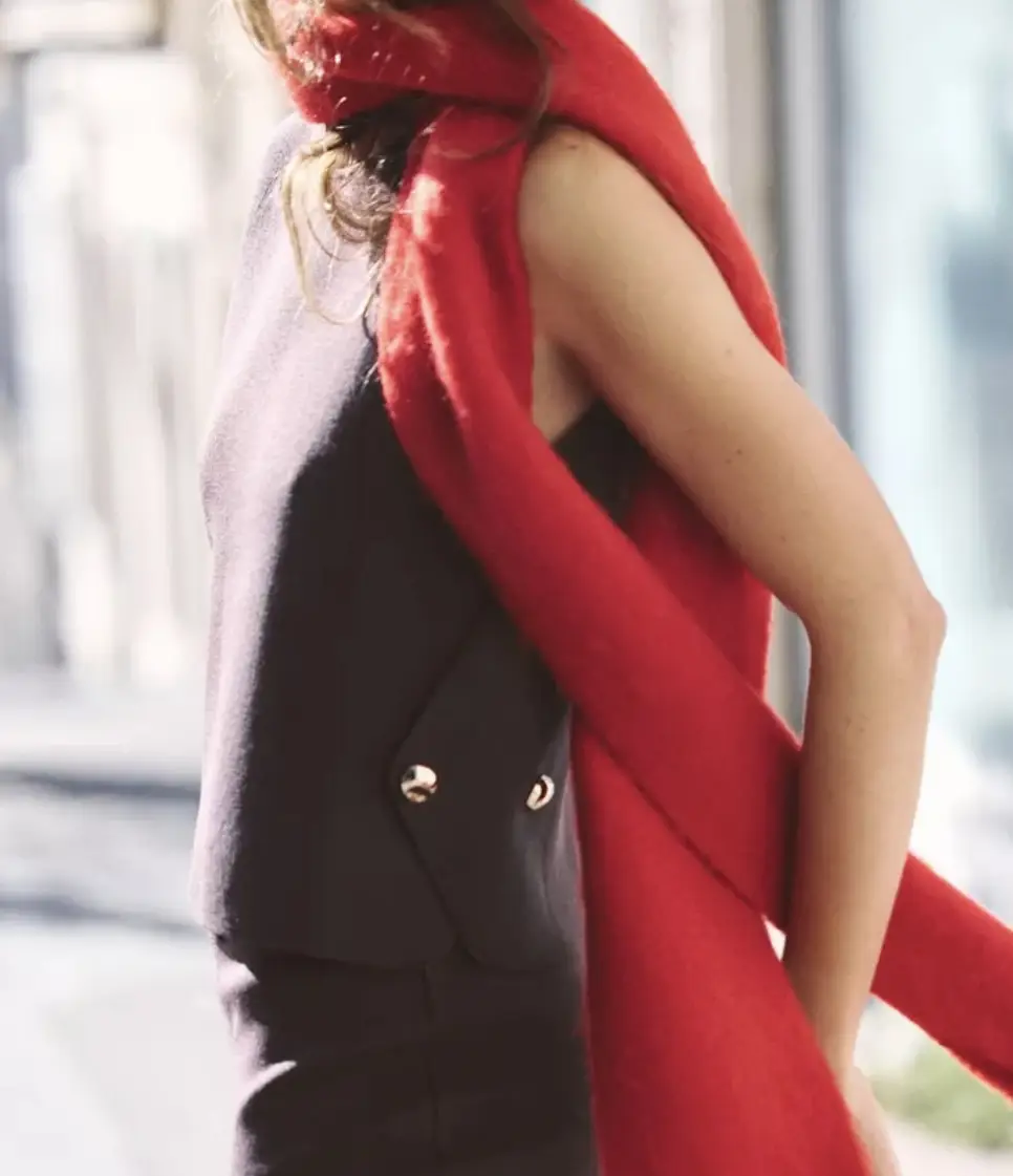 Top sin mangas de color marrón oscuro con detalles de botones dorados en los laterales. Ideal para combinar con una bufanda roja para un look moderno y sofisticado.