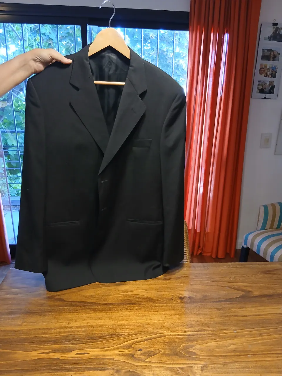 Saco negro de vestir, con solapa clásica y dos botones frontales. Posee bolsillos con tapa a los costados.