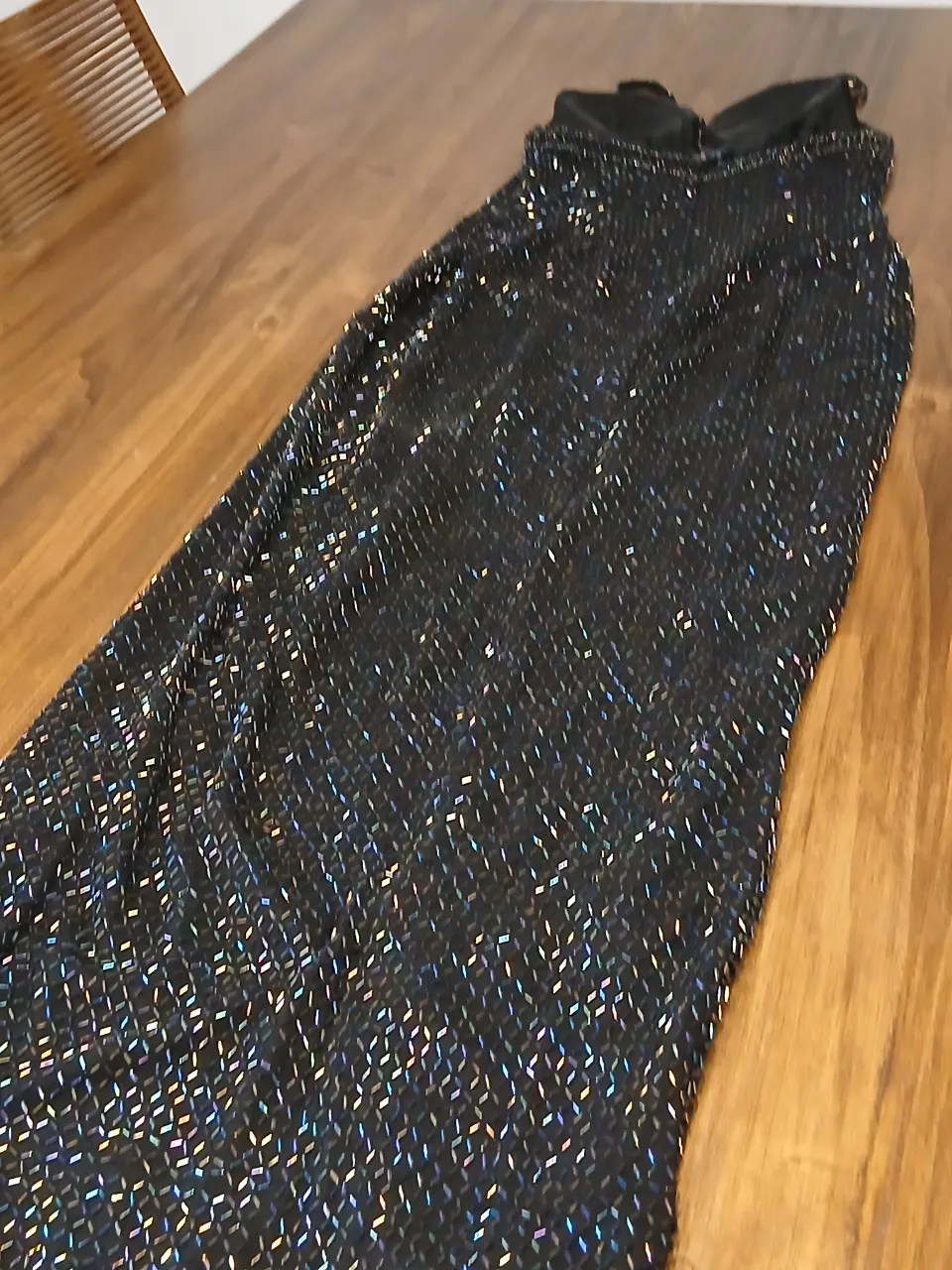 Vestido largo negro con brillos plateados y celestes. Posee un tajo lateral y breteles finos.