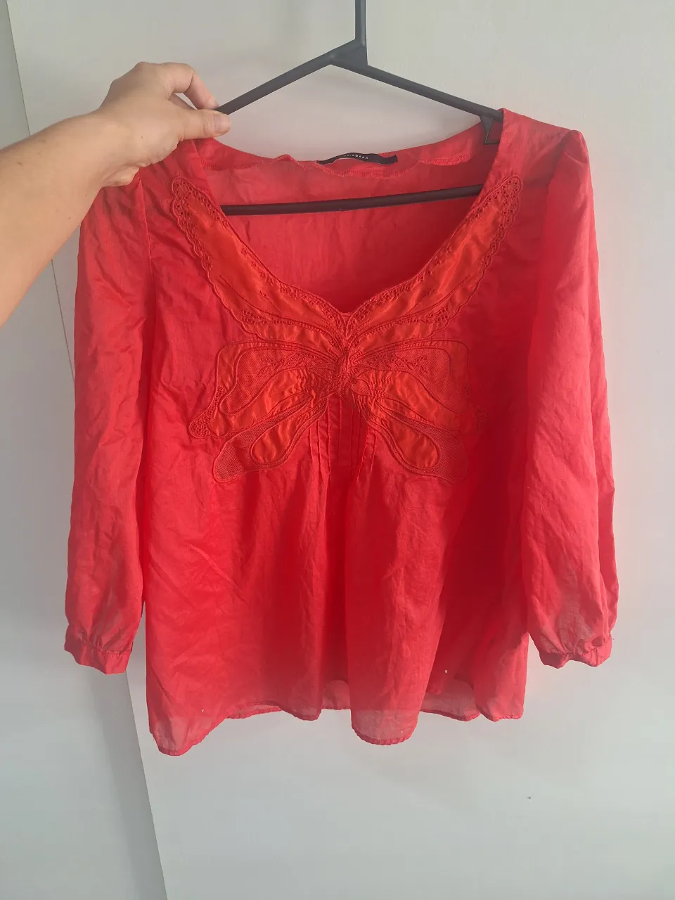 Blusa manga 3/4 en color rojo vibrante, con un delicado diseño de mariposa bordada en el frente. Escote en V con detalles sutiles. Perfecta para un look casual y femenino.