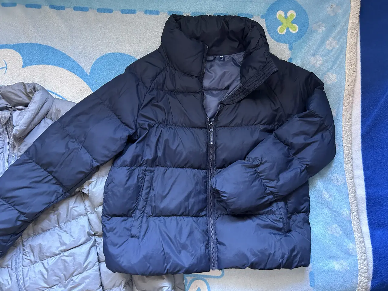 Campera de pluma azul marino de la marca Uniqlo, ideal para el invierno. Posee cierre y cuello alto.