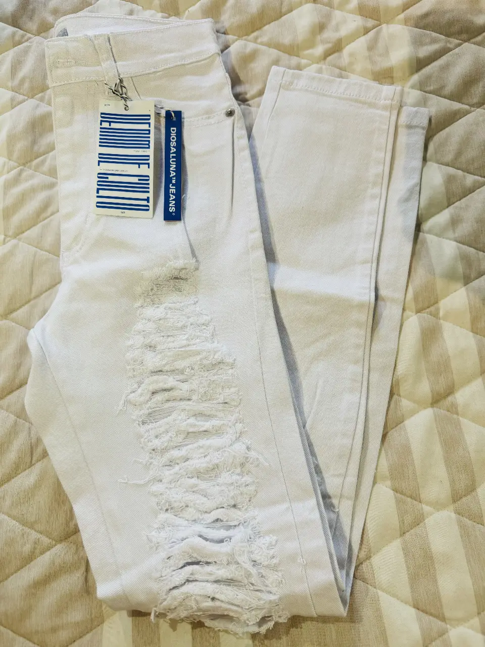 Jeans blancos rotos de mujer, tiro medio, con detalles de roturas en la parte delantera. Ideal para un look casual y moderno. 32cm de cintura. Elastizado.