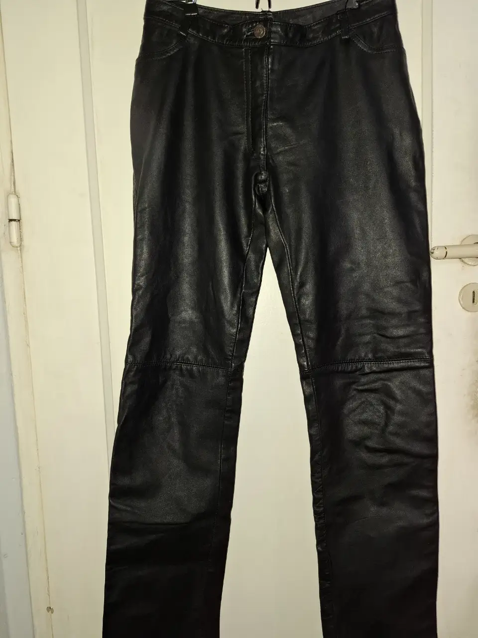 Pantalón de cuero negro, corte recto, tiro medio. Ideal para un look moderno y audaz. Perfecto para combinar con diferentes estilos.