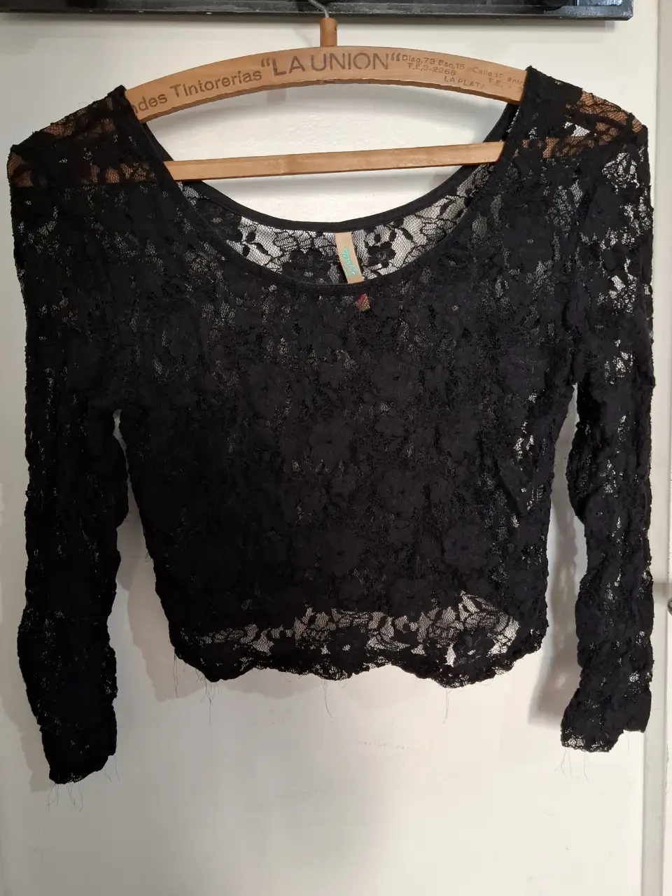Blusa de encaje negro, manga larga y corte crop. Ideal para looks de fiesta o para darle un toque romántico a tu outfit.