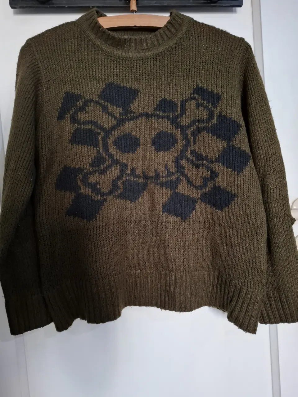Sweater de mujer de color verde oscuro con diseño de calavera en negro. Ideal para un look casual y canchero.
