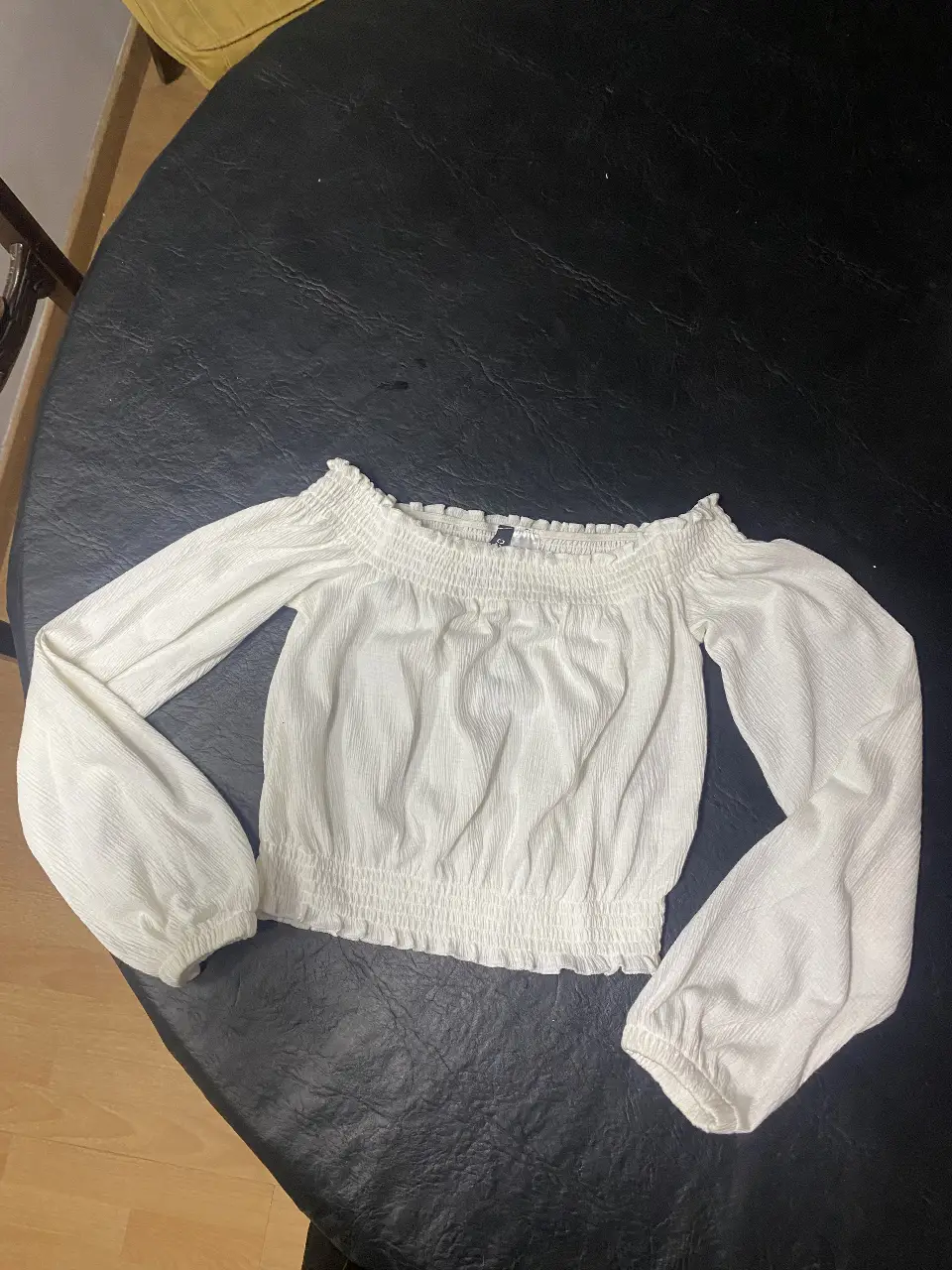 Blusa blanca de manga larga con detalle de fruncido en el cuello y puños. Ideal para un look casual y elegante.