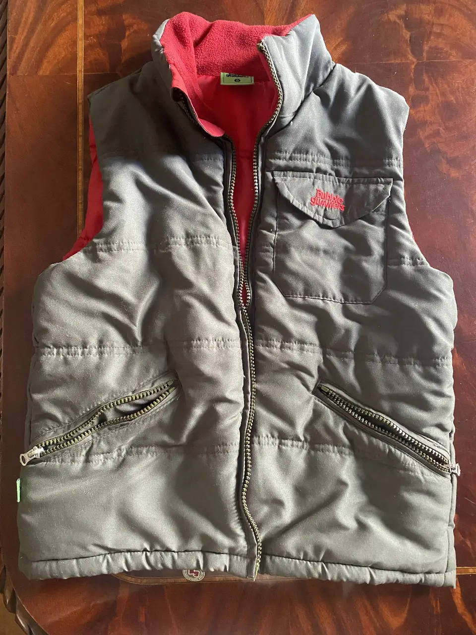 Chaleco acolchado para niño, color gris con interior rojo. Tiene cierre y bolsillos con cierre. Ideal para el invierno. de NIÑO 