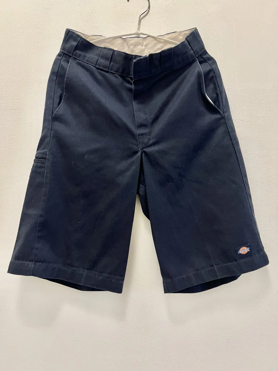 Shorts de gabardina azul marino con bolsillos frontales y traseros. Posee un pequeño logo de la marca en la parte inferior derecha.
