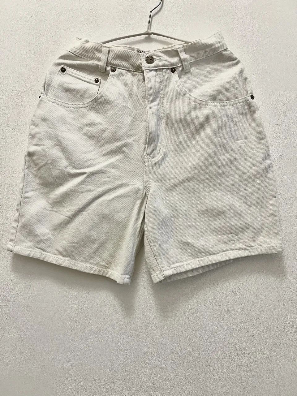 Shorts de jean color crudo. Modelo de cinco bolsillos con cierre y botón.