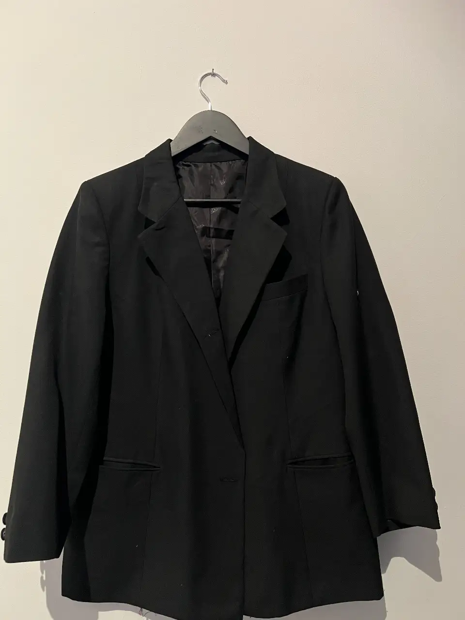 Blazer negro de corte clásico, ideal para un look formal o de trabajo. Confeccionado en tela resistente, presenta dos bolsillos delanteros y un diseño atemporal.