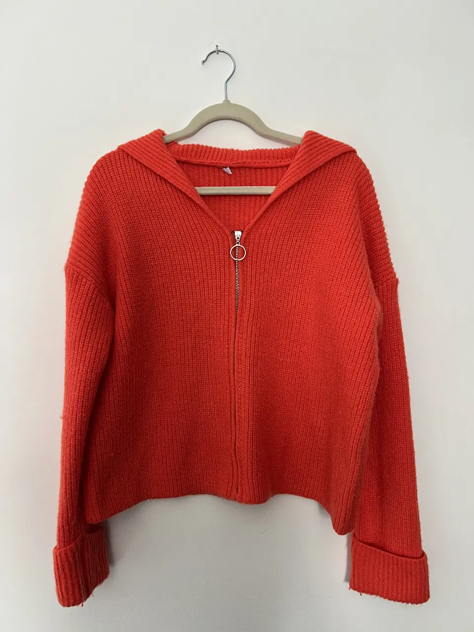 Sweater largo de tejido grueso con capucha y cierre frontal. Ideal para un look casual y abrigado en invierno. Confeccionado en un vibrante color naranja.