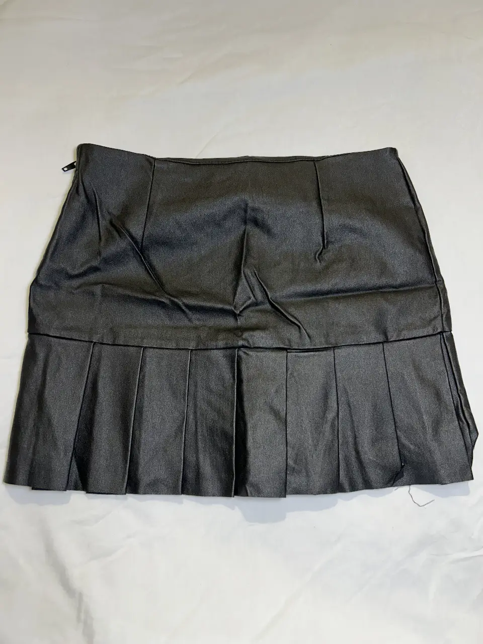 Minifalda de cuero sintético plisada, ideal para un look moderno y audaz. Perfecta para combinar con diferentes estilos y crear outfits únicos.