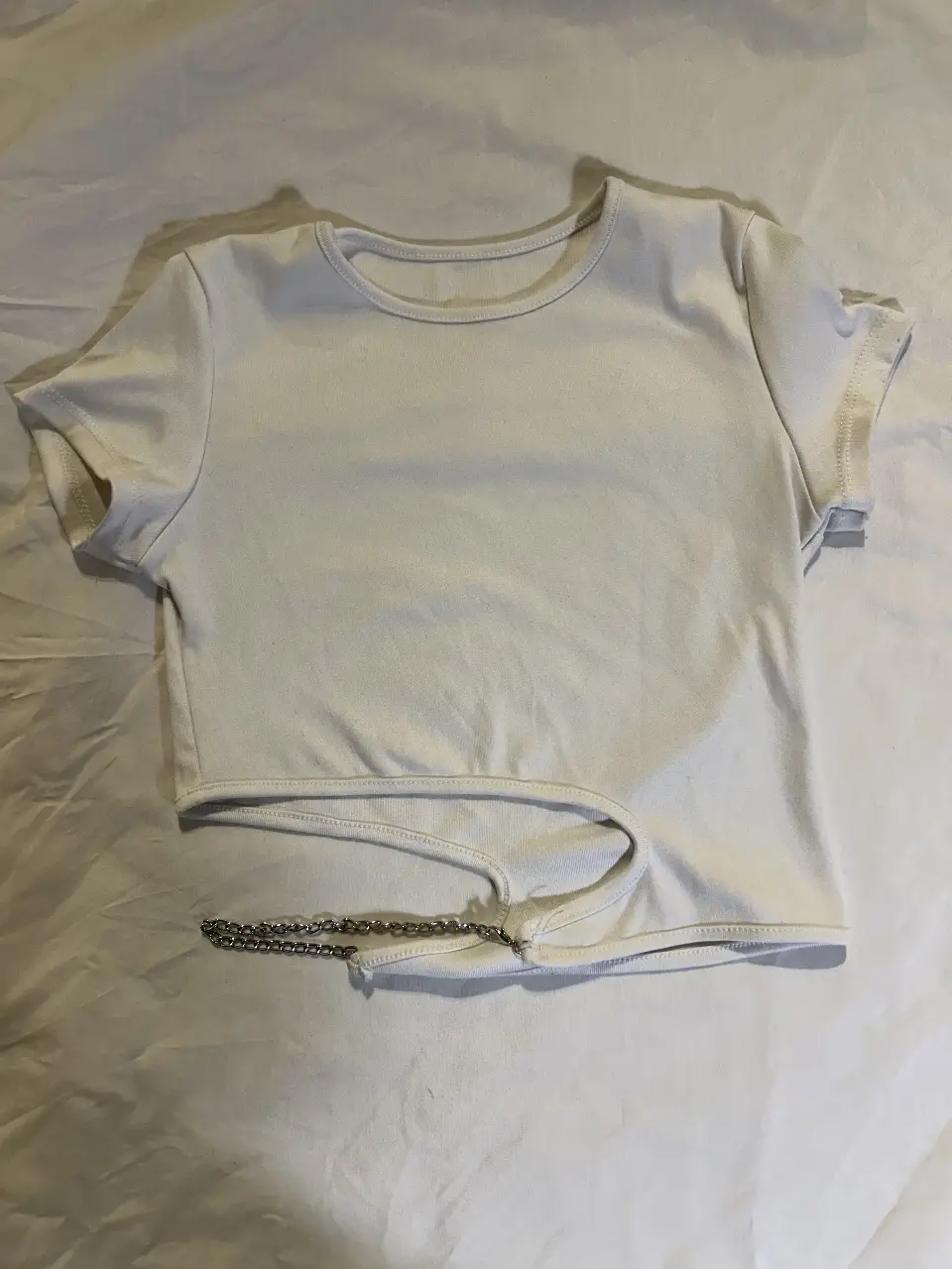 Top blanco con detalle de cadena. Ideal para un look moderno y canchero.