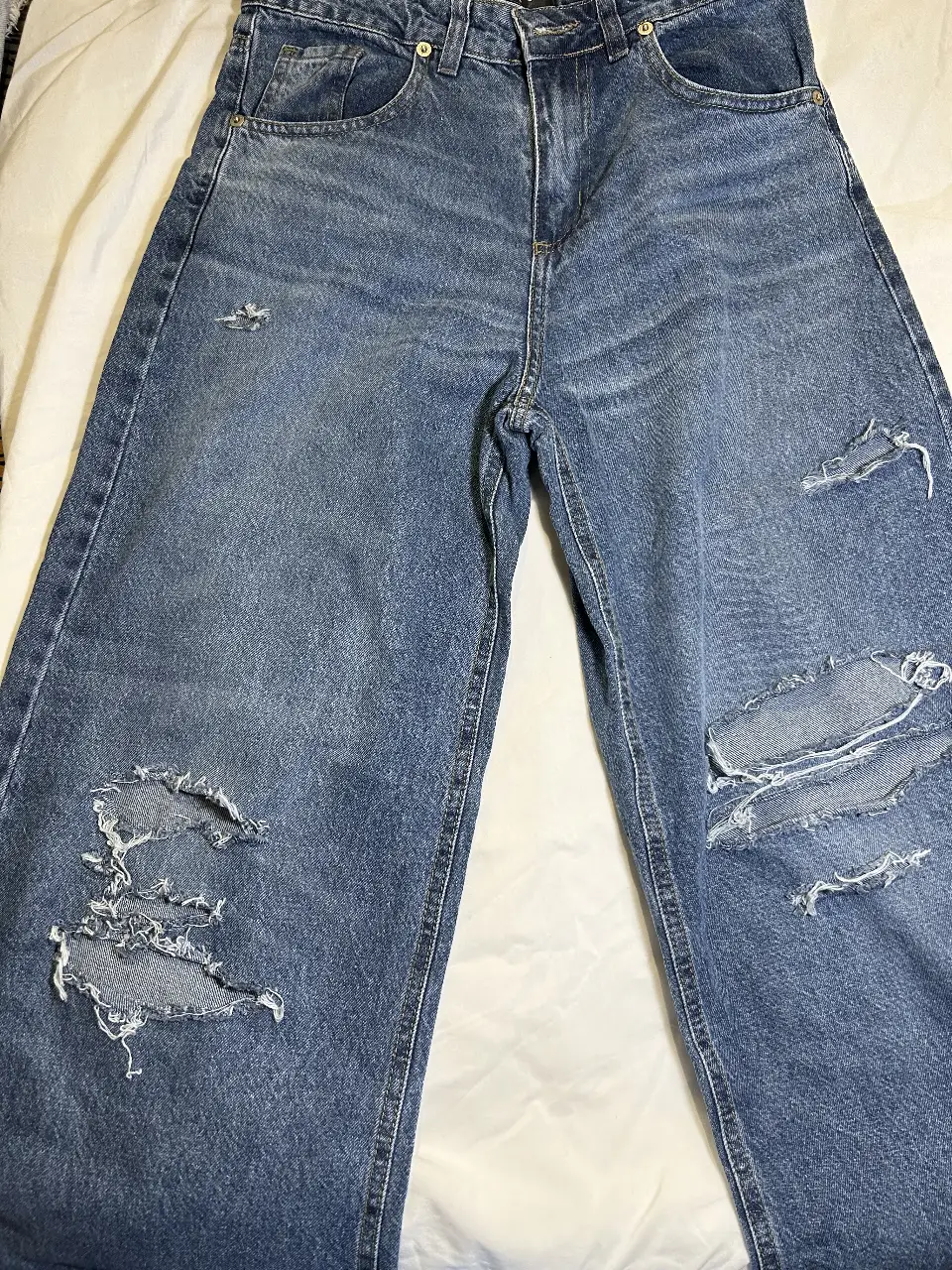 Jeans de mujer, tiro medio, con roturas en las rodillas y corte ancho. Ideal para un look urbano y relajado.
