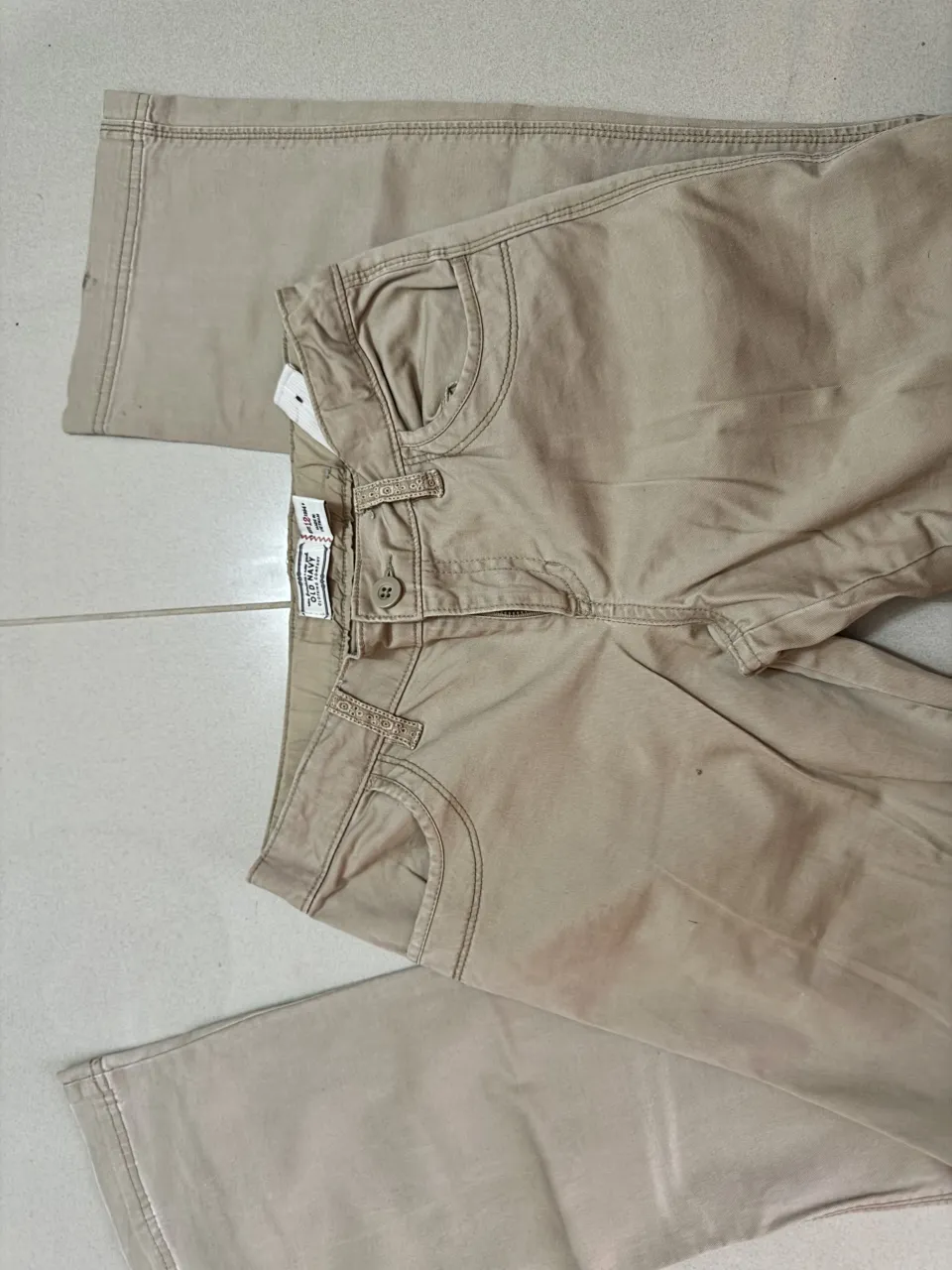 Pantalones color beige con bolsillos cargo en la parte trasera. Cuentan con cierre y botón en la parte delantera.