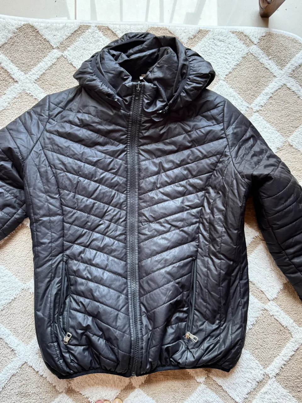 Campera negra acolchada con capucha y cierre completo. Posee bolsillos laterales con cierre. Tiene peluche adentro