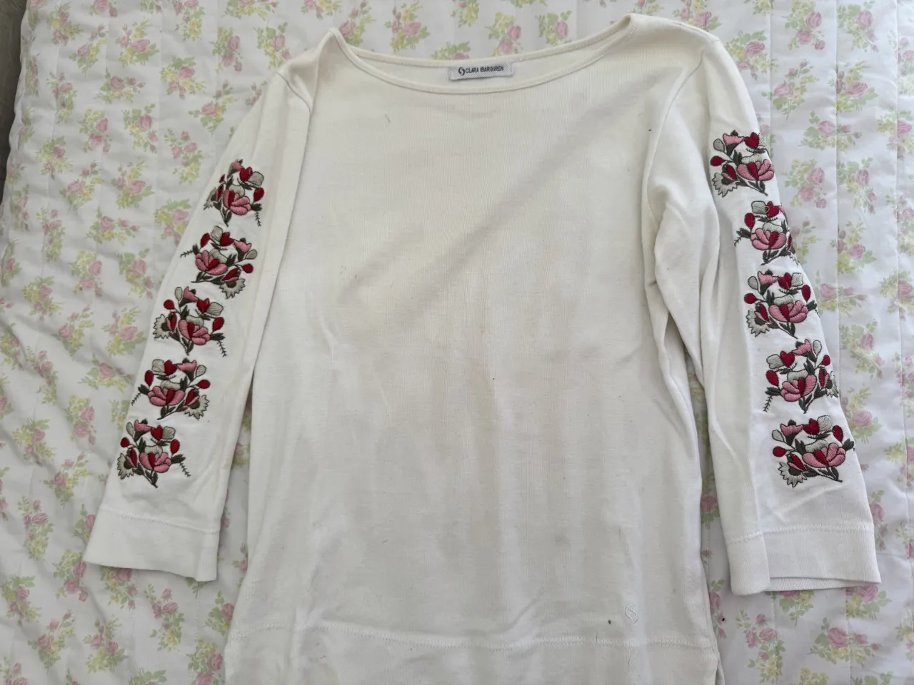 Remera blanca de manga 3/4 con bordados de flores en las mangas. Escote redondo.