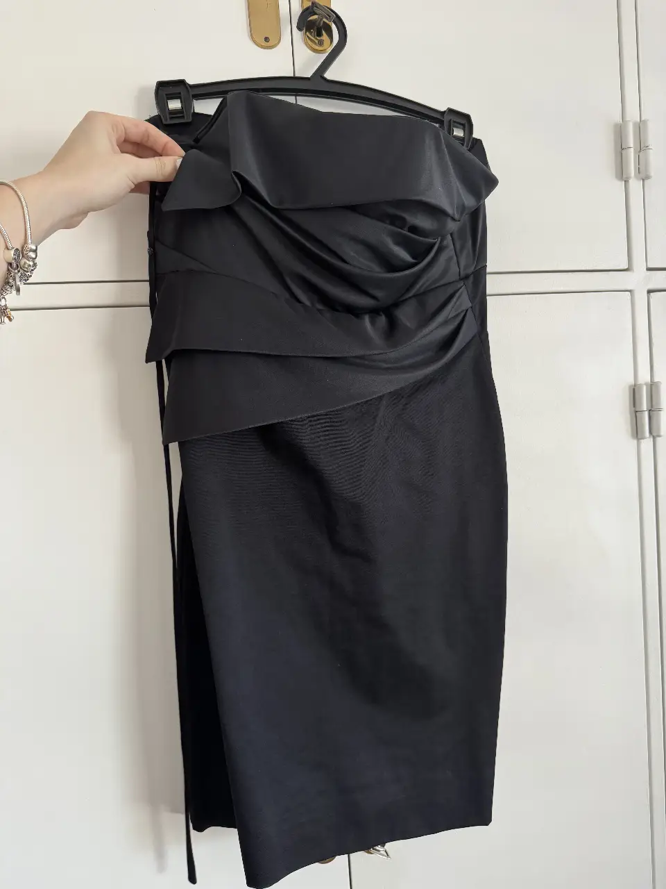 Vestido strapless negro de la marca Unicke, ideal para eventos formales o fiestas. Con un diseño elegante y detalles drapeados, este vestido midi ofrece un ajuste favorecedor y un estilo sofisticado.