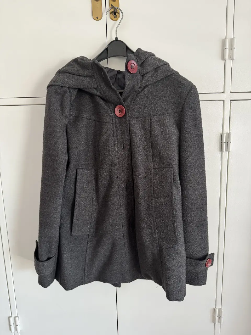 Tapado gris con capucha y botones rojos. Ideal para el invierno, este abrigo es perfecto para un look casual y abrigado.
