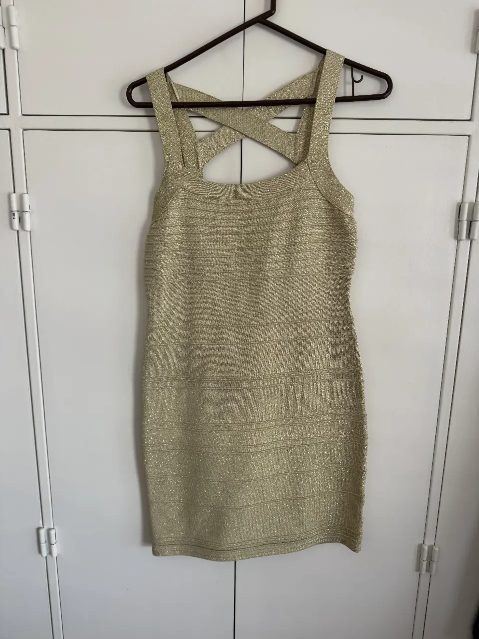 Vestido mini dorado de Wow Couture, con diseño cruzado en la espalda y detalles brillantes. Ideal para fiestas y eventos especiales. Talle L que es más un M.