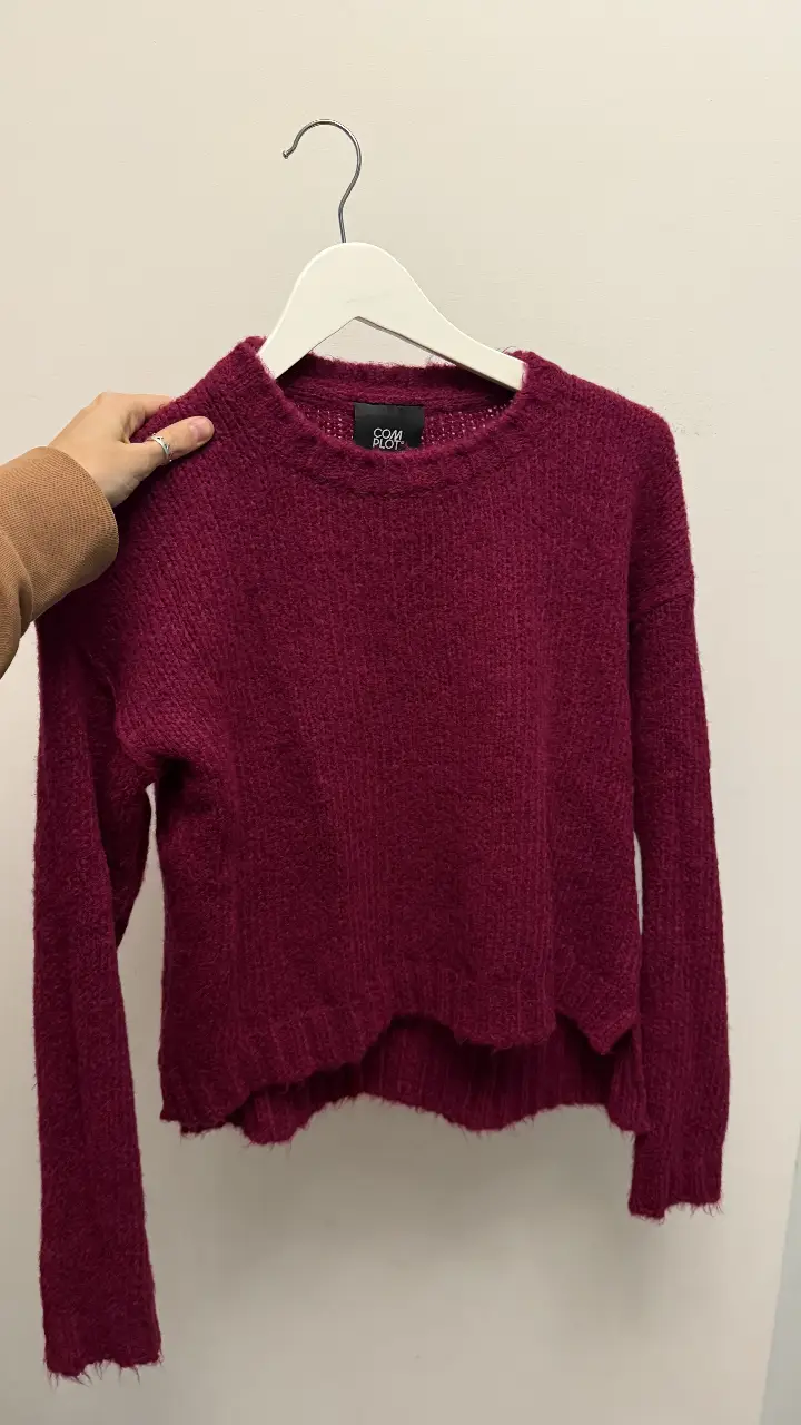 Sweater de color borgoña, con cuello redondo y corte asimétrico. Ideal para un look casual y abrigado.