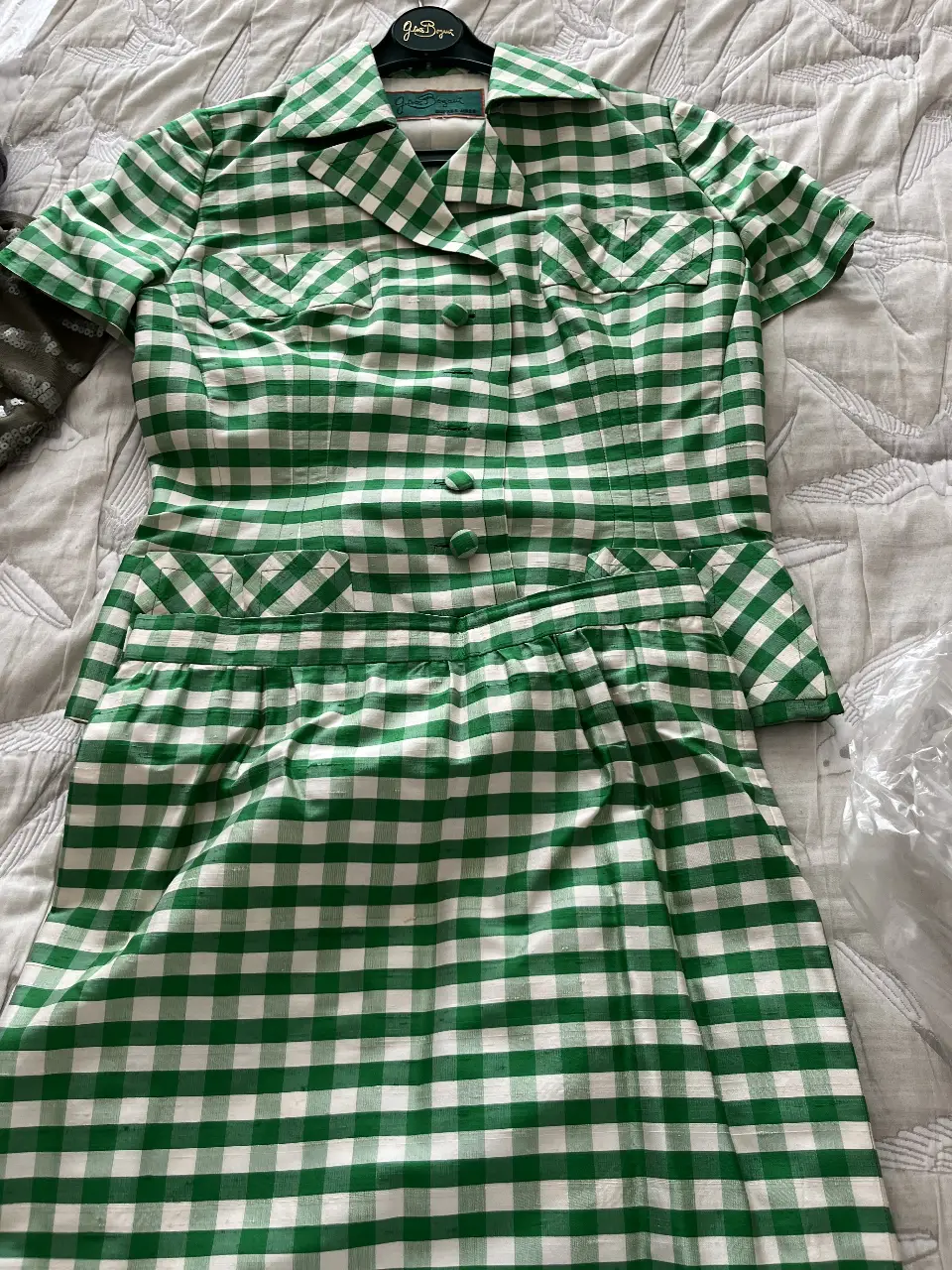 Conjunto vintage de camisa y falda a cuadros verdes y blancos. La camisa tiene mangas cortas, bolsillos delanteros y botones. La falda es de corte evasé con detalles en la cintura. Ideal para un look retro y fresco.