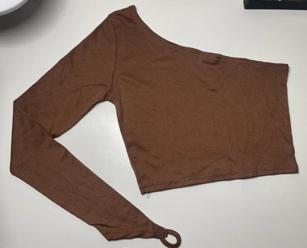 Top asimétrico de un solo hombro en color marrón. Ideal para un look moderno y audaz.