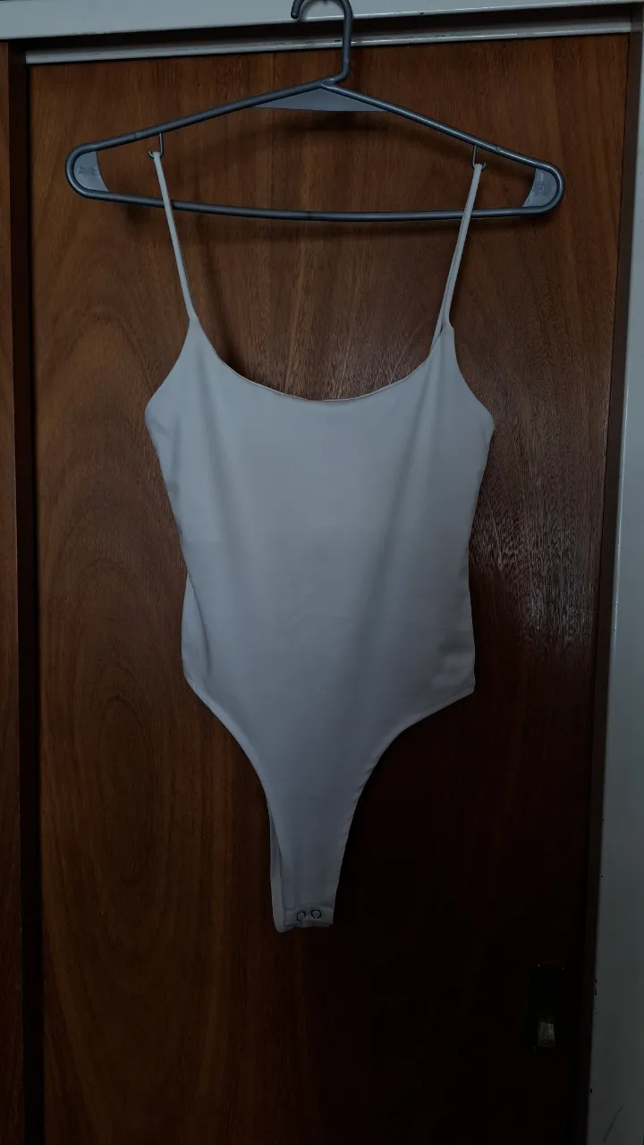 Body de tiras finas color blanco. Posee broches en la parte inferior y doble tela en el pecho. La tela es brillosa. Tiene un calce re lindo, se amolda al cuerpo.