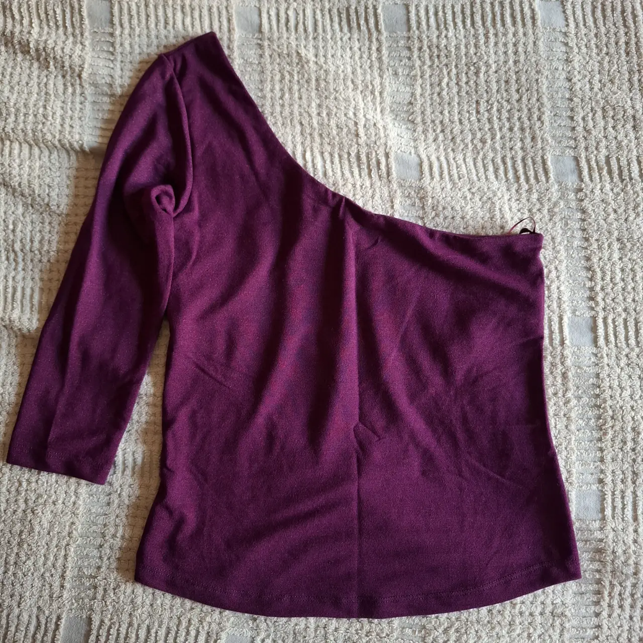 Blusa de un solo hombro, color vino con brillitos, de la marca Cuesta Blanca. Talle 42.