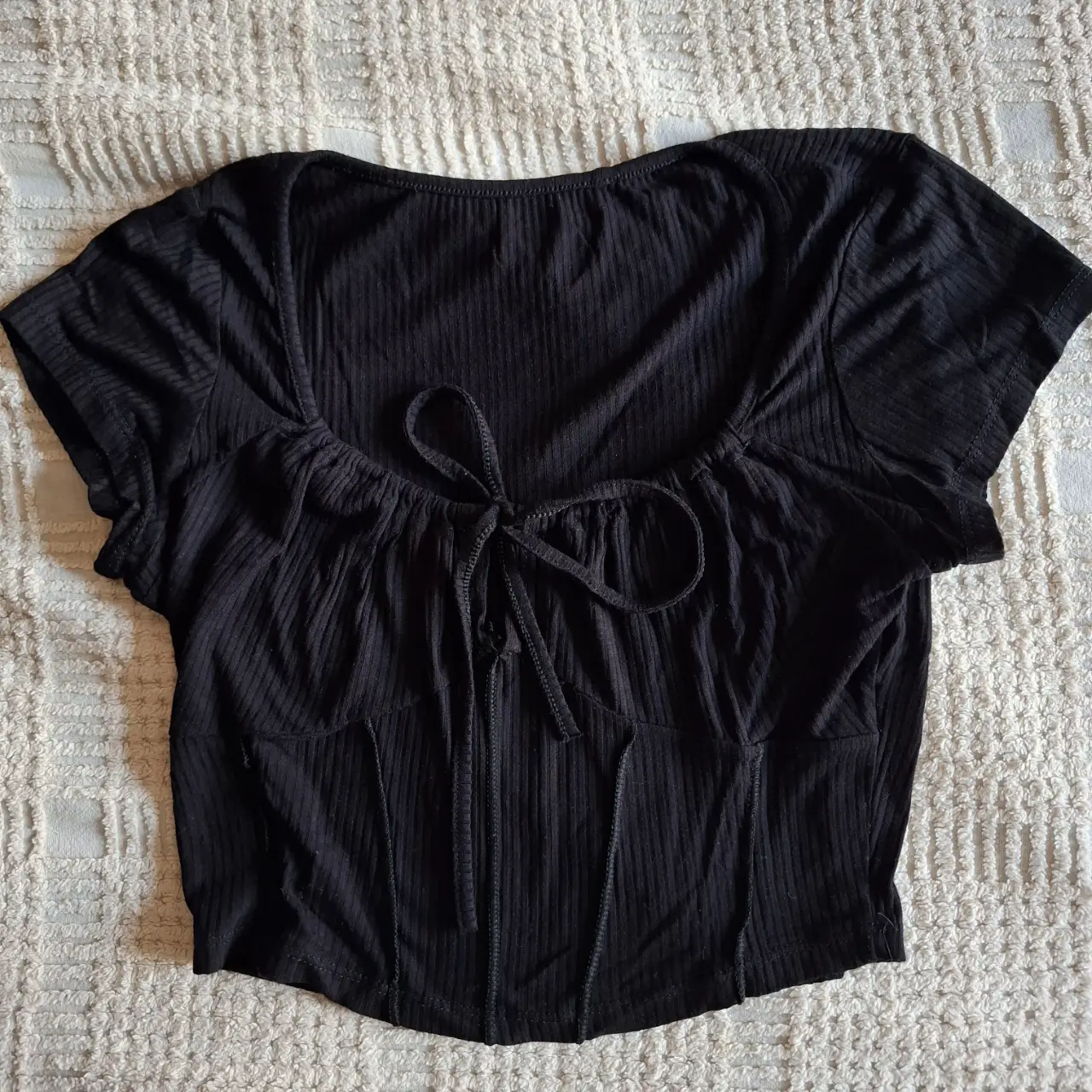 Top negro con detalle de lazo en el frente y corte tipo corset. Ideal para un look moderno y sofisticado.