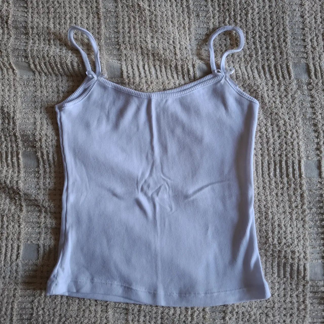 Musculosa blanca de algodón, con breteles finos y detalle de moño. Ideal para combinar con cualquier look casual.