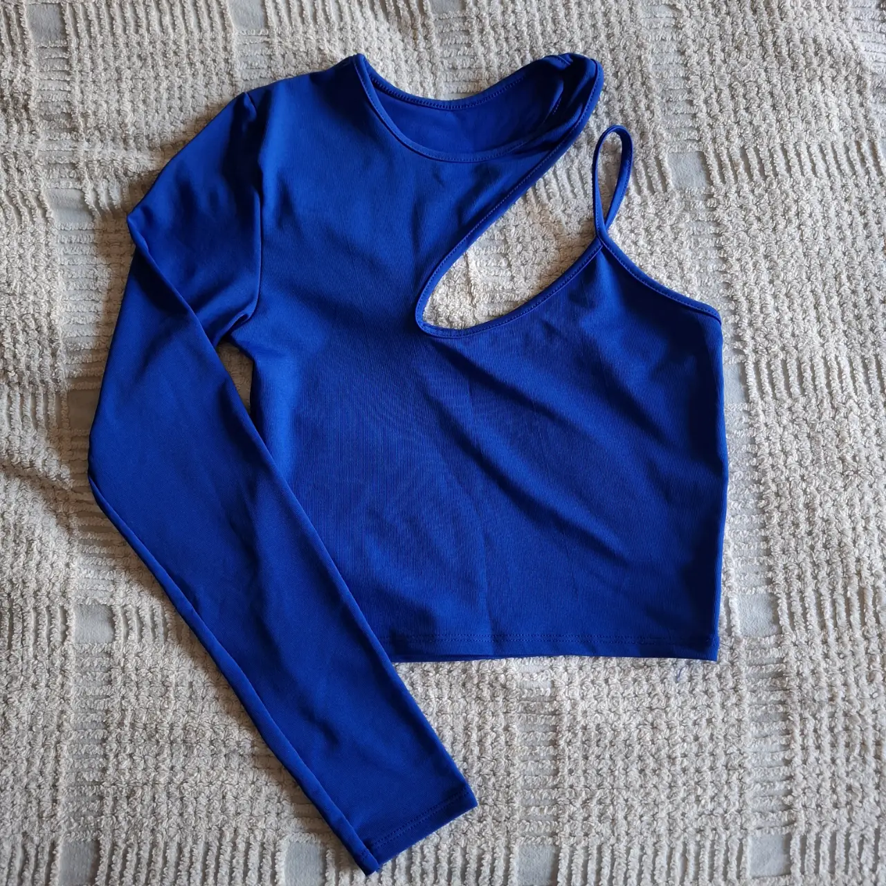 Top asimétrico de manga larga en color azul eléctrico. Diseño moderno con un hombro descubierto y un corte en el pecho. Ideal para un look audaz y a la moda.